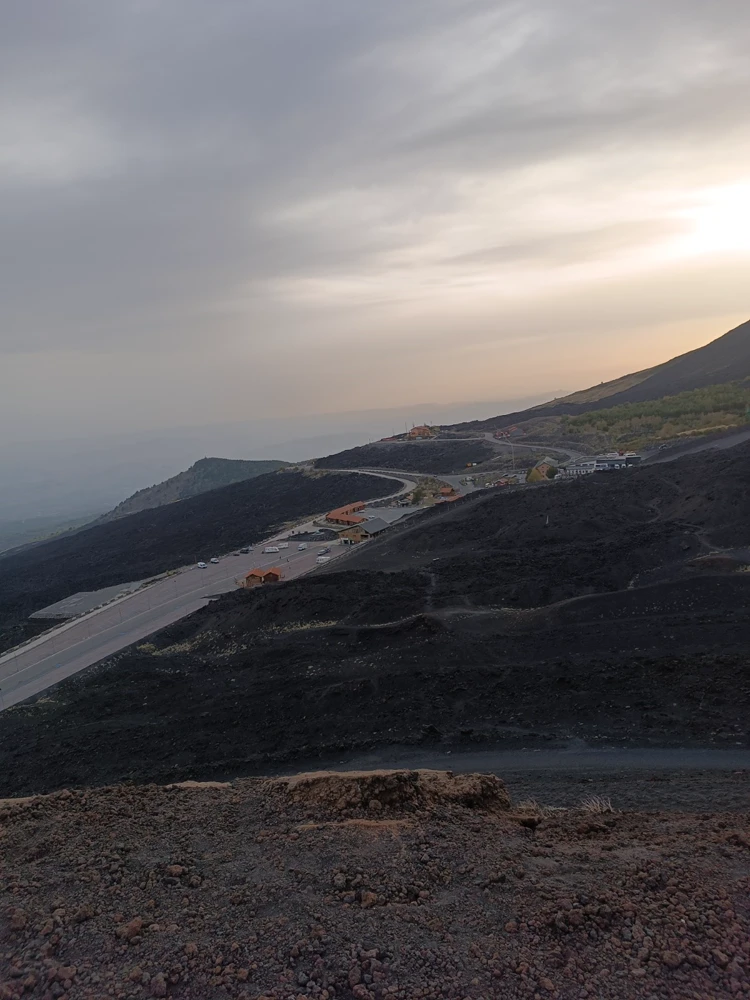 Versant de l’Etna au crépuscule, route sinueuse sur la lave noire.
