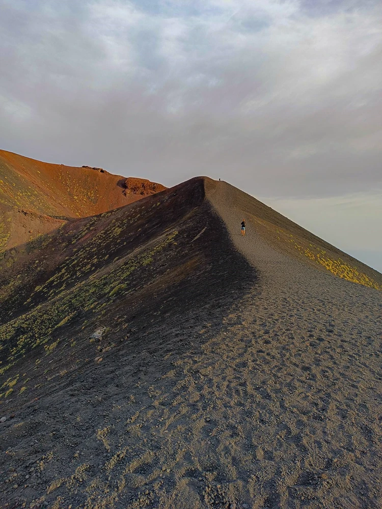 Crête de cendre noire de l’Etna, une marcheuse minuscule sur l’arête.