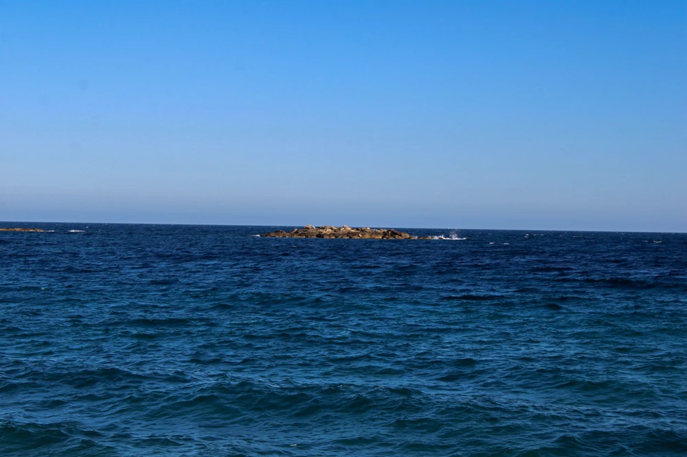 Un petit îlot rocheux seul sur une mer bleue profonde.