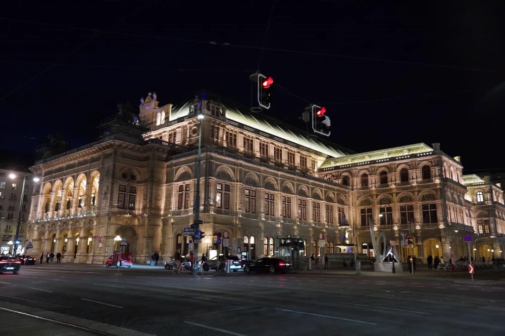 L’Opéra de Vienne illuminé la nuit à l’angle d’un boulevard.